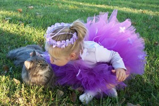 A toddler girl in a fluffy DIY no-sew tulle tutu skirt that's purple with a matching purple headband.