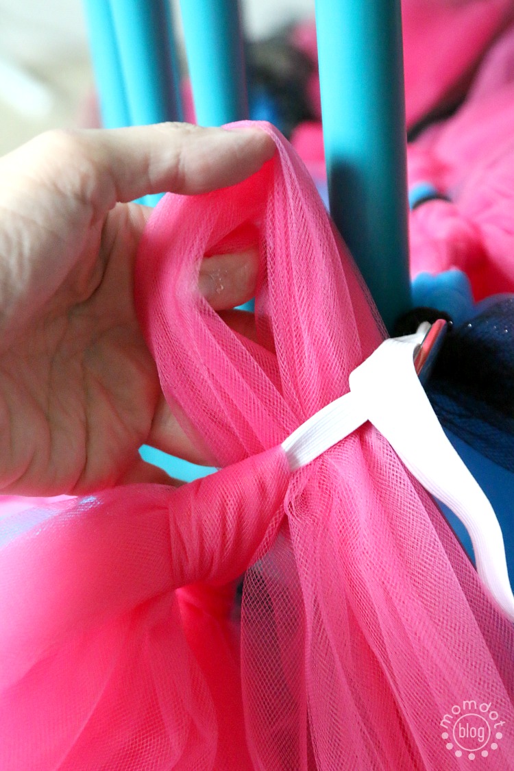 Tulle loop being pulled through the prepared elastic waistband to begin tying it on in a slip knot.
