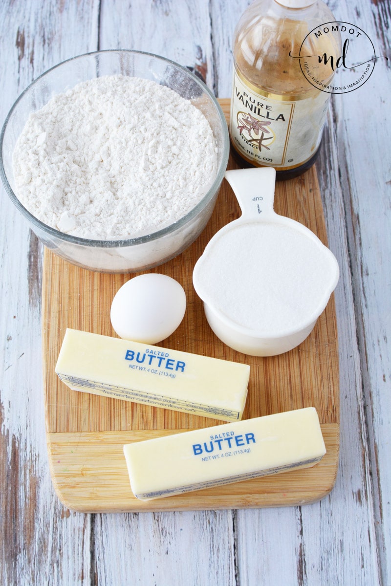 Flour, sugar, butter, egg, and vanilla on a cutting board to make Country Crock sugar cookies.