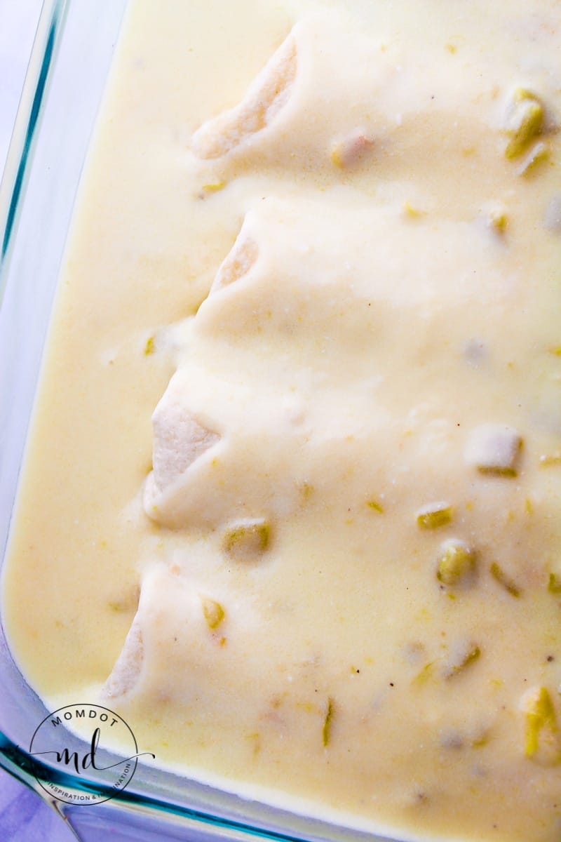 White chicken enchiladas in a baking pan and covered with creamy white sauce.