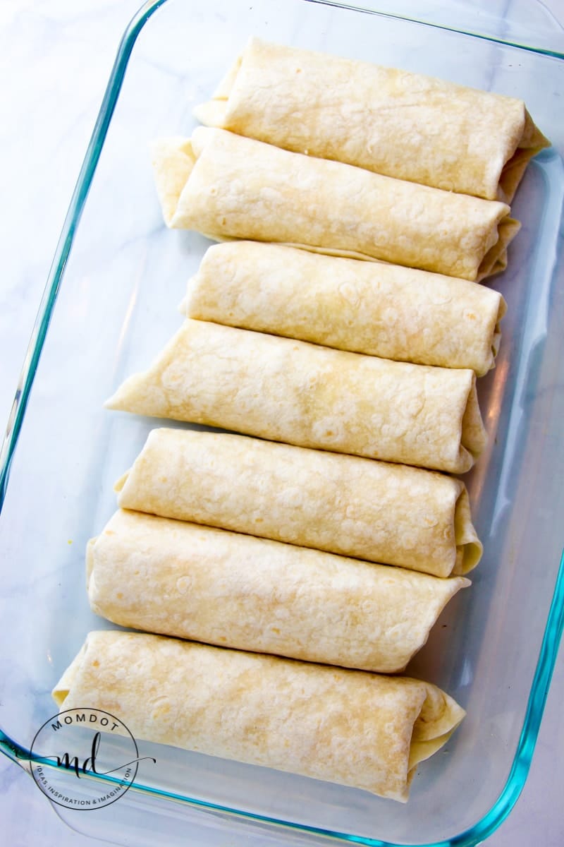 Rolled white chicken enchiladas in a baking dish.