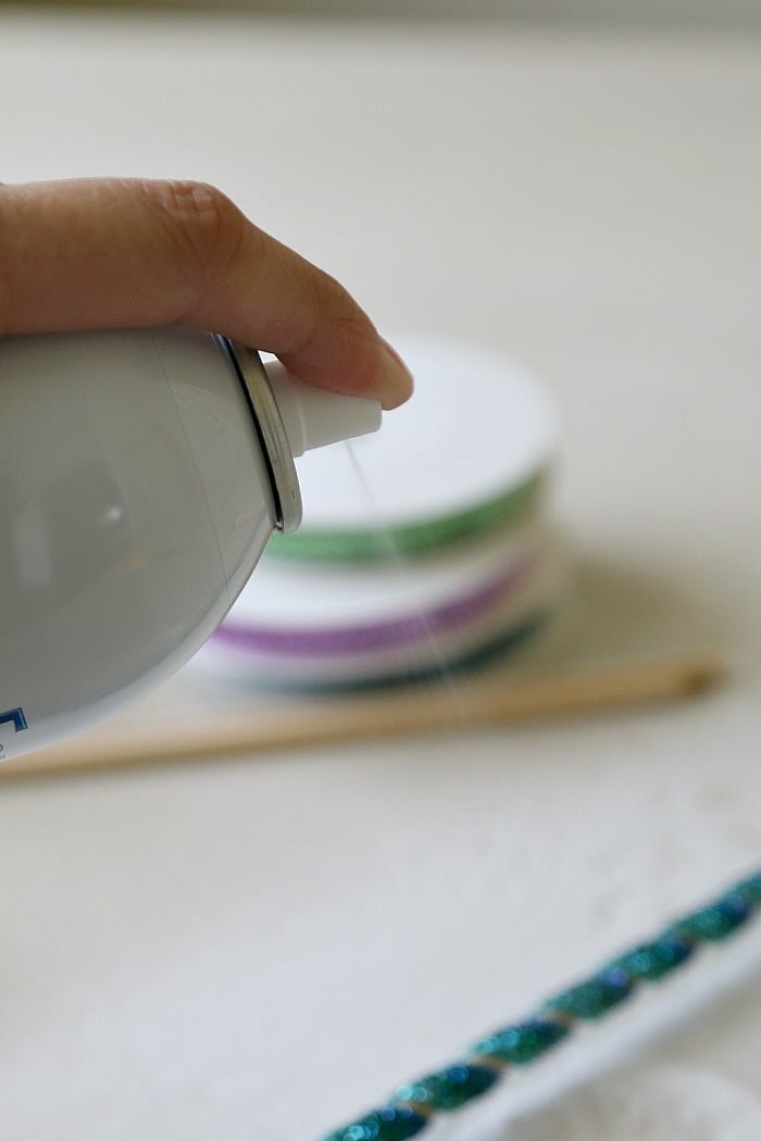 Spraying starch on the ribbon wrapped around a wooden dowel so that it will stay in the spiral korker shape.