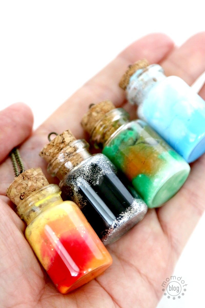 Up close photo of finished element jar necklaces, showing the finished cork tops and glitter inside with the bright paint.