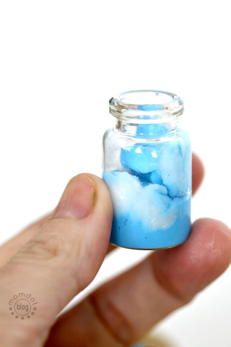 An element jar necklace representing the sky is filled with blue and white paint.