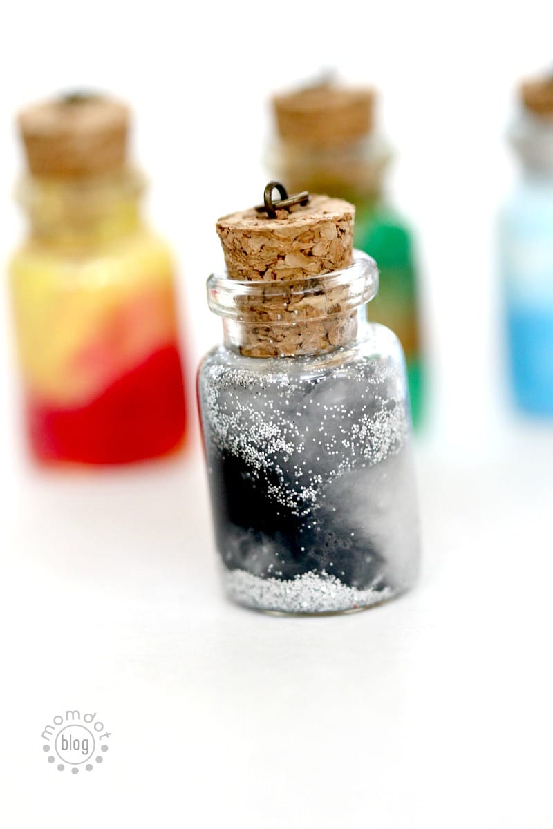 A finished moon elements jar necklace features black paint inside with silver glitter at the bottom and top of the jar.