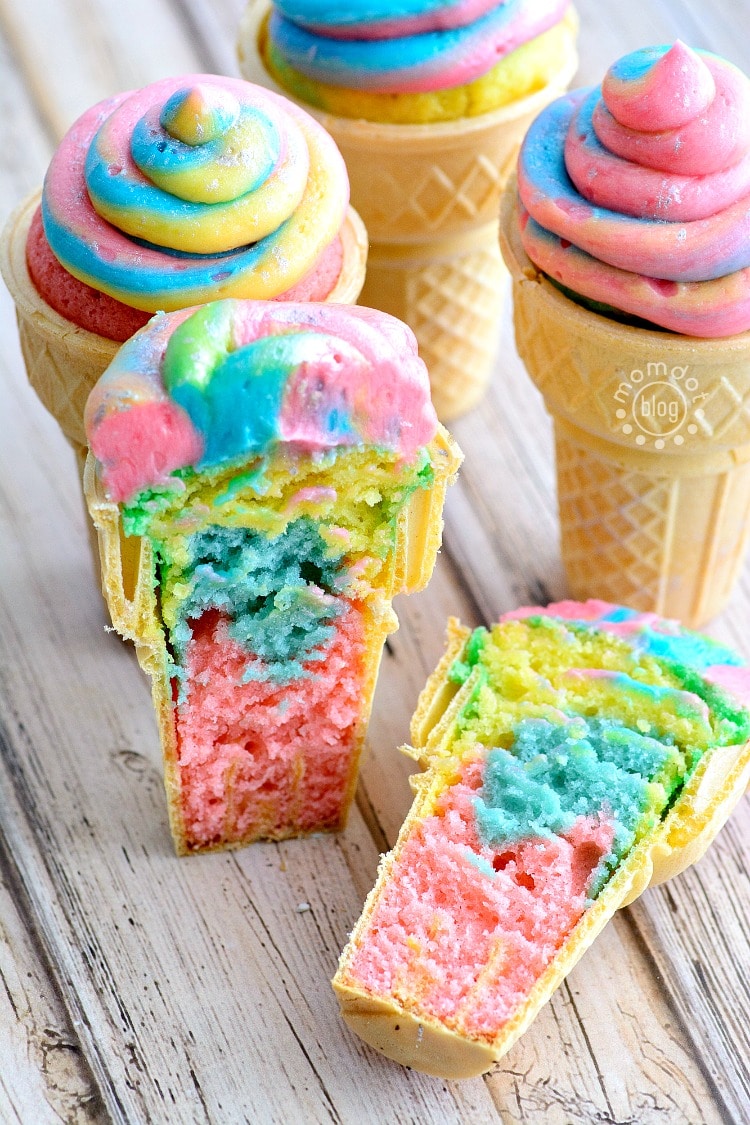 Finished unicorn poop cupcakes baked in ice cream cones. One is sliced in half to show color and texture running throughout.