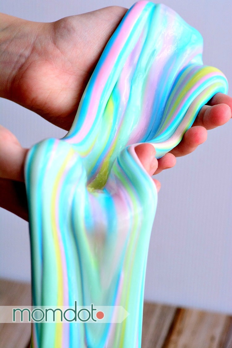 Unicorn slime is a rainbow of pastel colors dripping from a pair of hands to show the uniform texture.