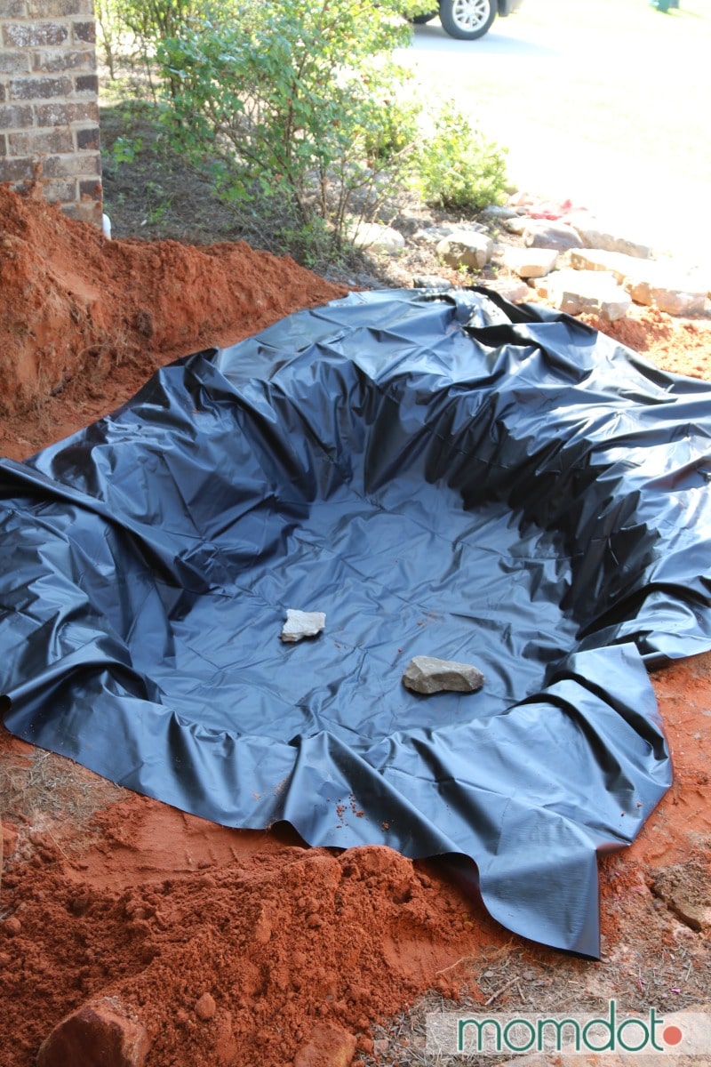 A black pond liner placed inside a fresh hole dug for a new pond