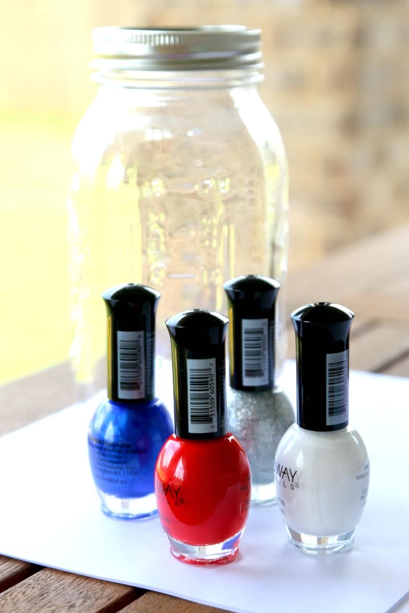 A mason jar and 4 colors of nail polish in red, white, blue, and silver glitter to make marble dip jars.