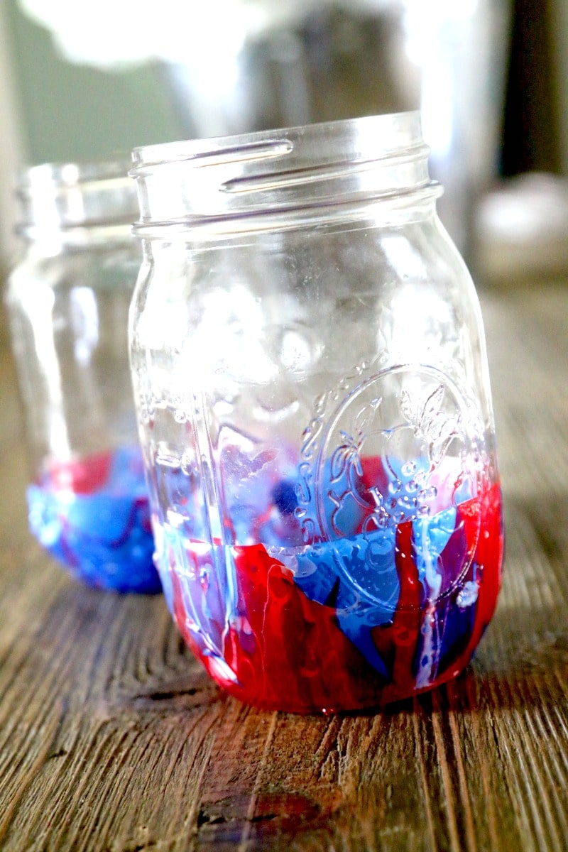 Finished red, white, and blue marble dip mason jars sitting on a table. 