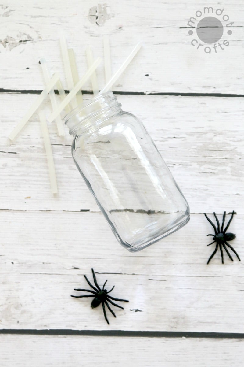 Mason jar, fake spiders, and hot glue sticks to make a spider jar for Halloween