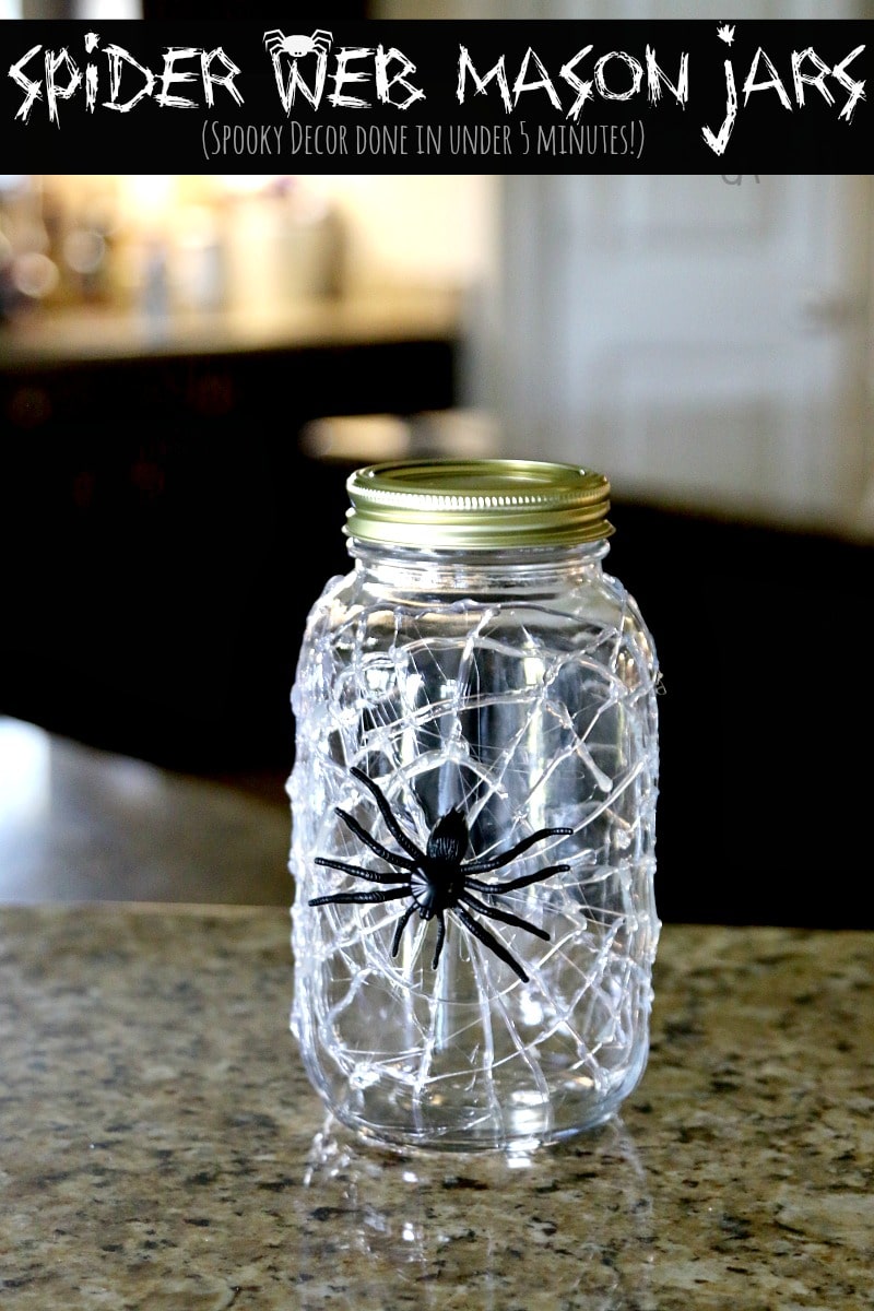 A jar with hot glue spider web on the outside and a giant fake spider stuck to it