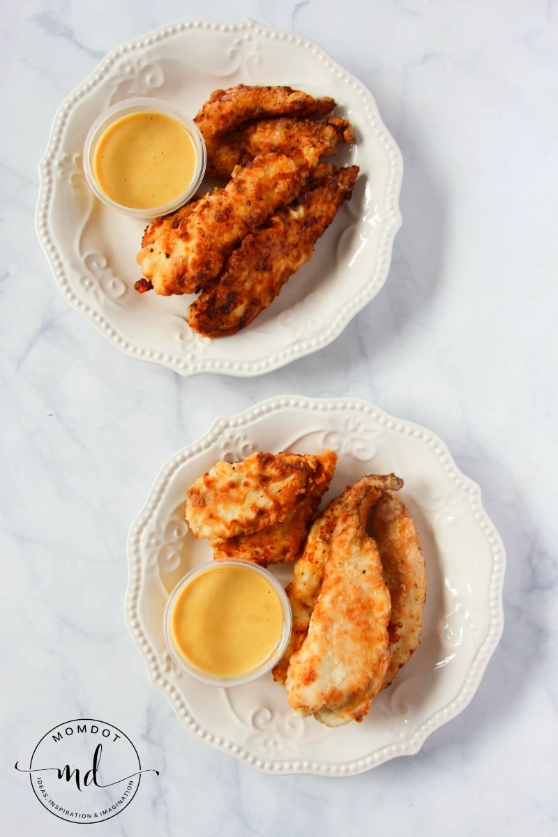 Copycat Chick-fil-A chicken tenders and a cup of honey mustard dressing on a white plate