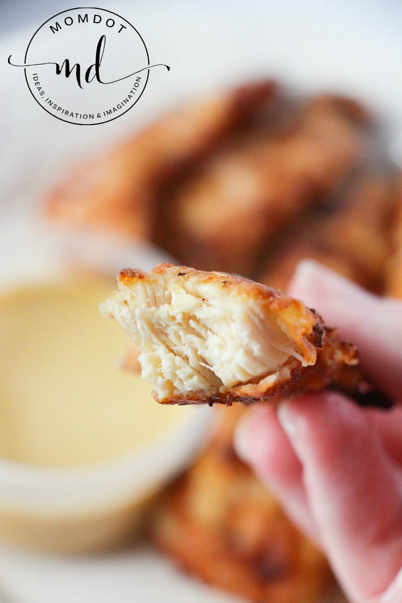 A copycat Chick-fil-A chicken strip broken in half showing a tender, white texture inside.