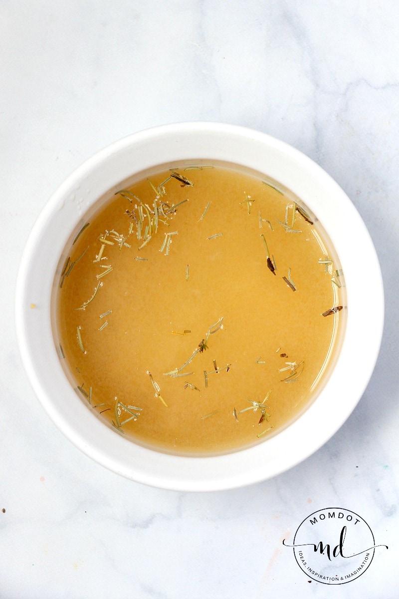 Chicken broth in a bowl with herbs