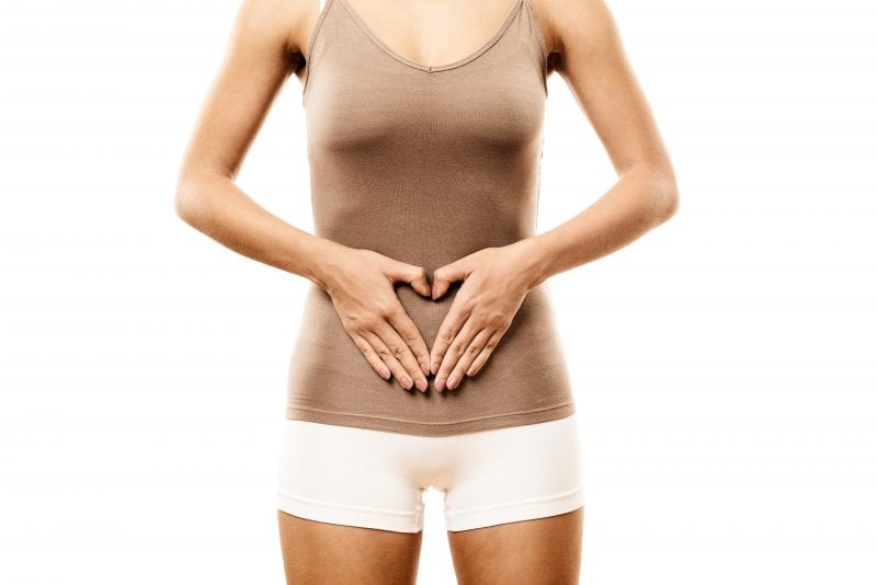 Thin woman making a heart shape with her hands in front of her abdomen