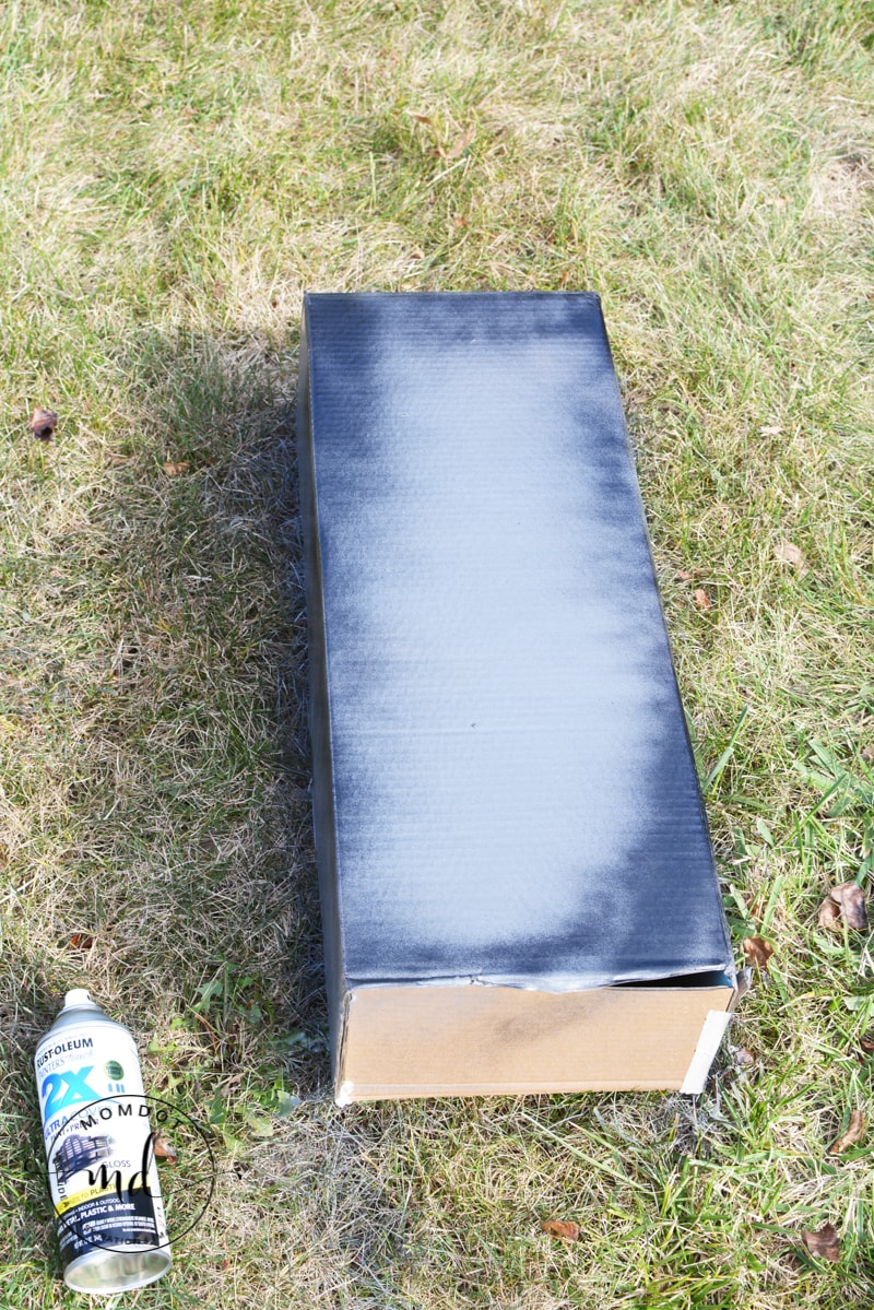 Decorative spray painted cardboard tombstone laying on the grass