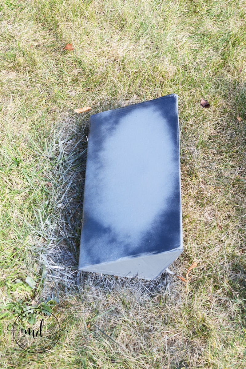 A small triangle of cardboard that is spray painted to make a small tombstone decoration