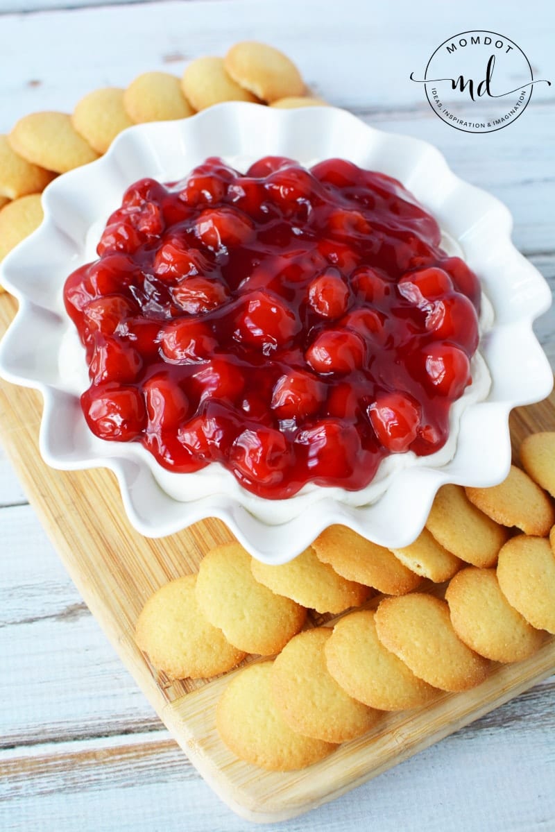 Cherry cheesecake dip in a fancy bowl surrounded by vanilla wafers