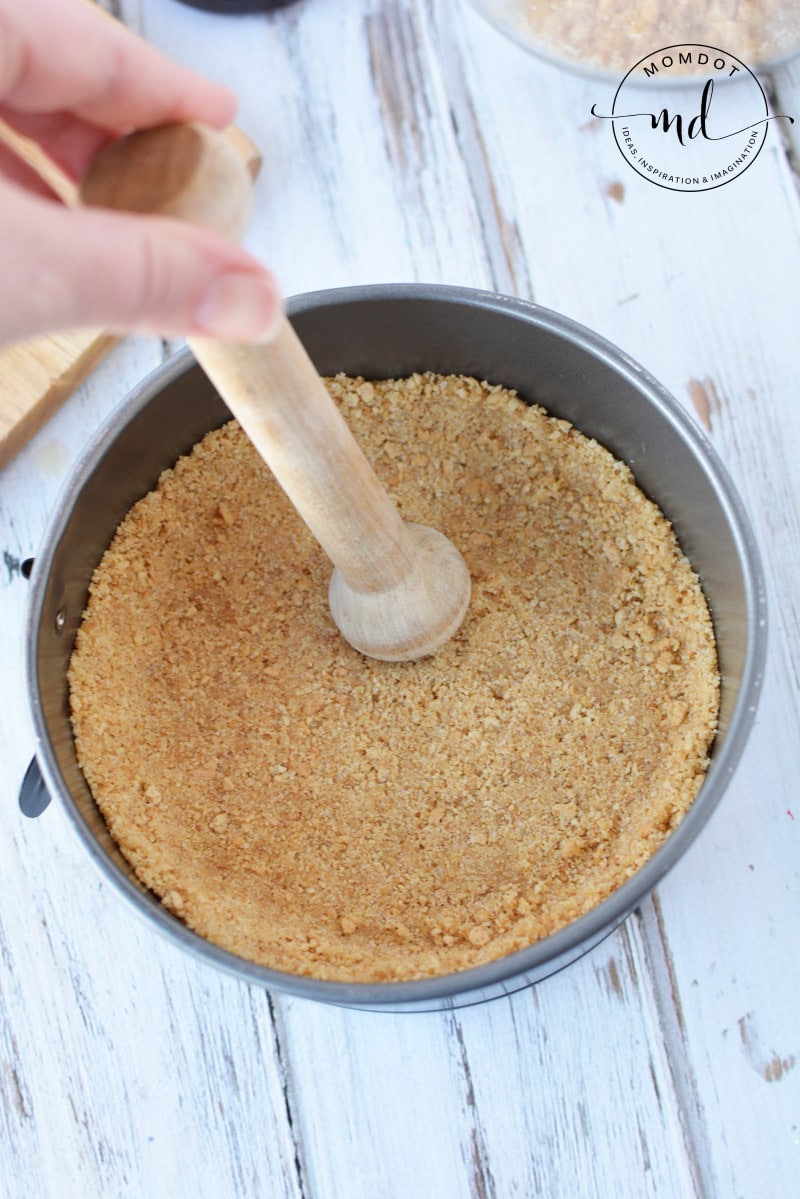 Using a pastry tart shaper to press the graham cracker crust into a small 6-inch springform pan for Instant Pot cheesecake.