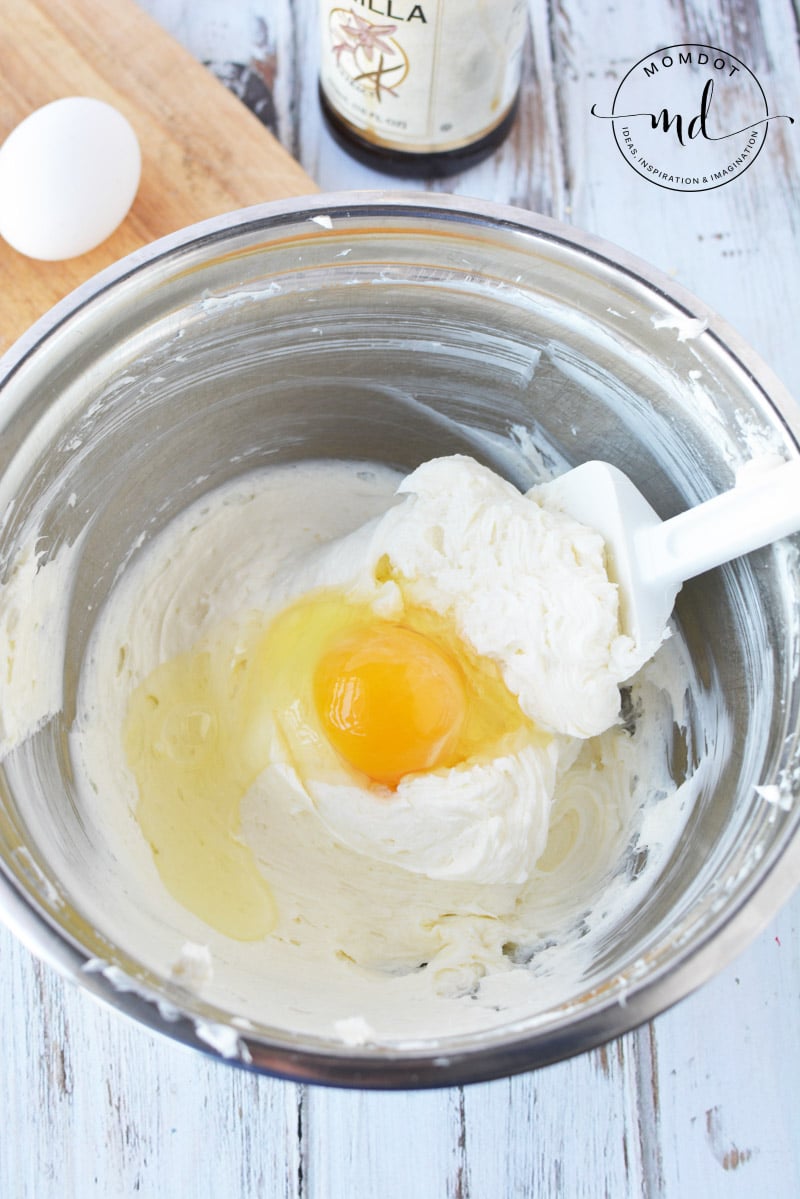 Mixing eggs and sugar into the cream cheese to make a cheesecake