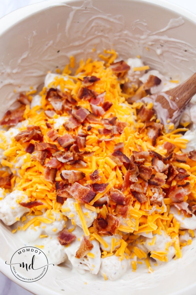 Tater tot casserole mixture with bacon and cheese on top to be stirred in before baking.