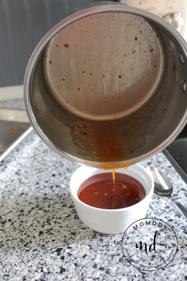 Pouring the Asian Zing wing sauce out of the saucepan into a small bowl.