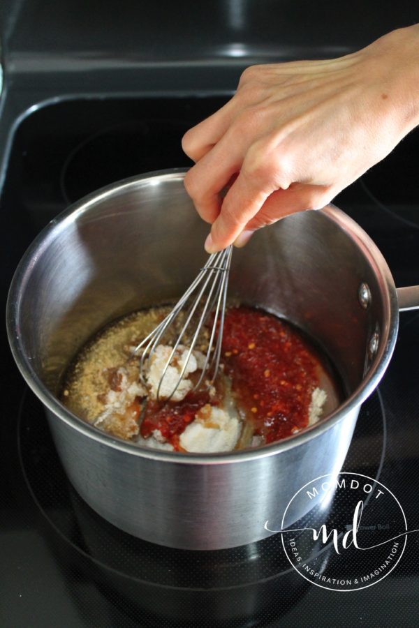 Whisk mixing Asian Zing wing sauce ingredients together in a saucepan.