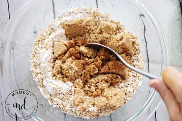 A spoon in a bowl of ingredients that get mixed together to make apple crisp topping.