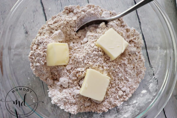 Margarine cut in pieces, placed on top of apple crisp topping ingredients that will be incorporated with a pastry blender.