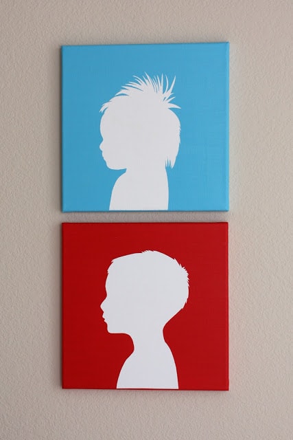 Two canvas silhouette paintings of children, one in red and one in blue, painted as a DIY Christmas gift for Grandma.
