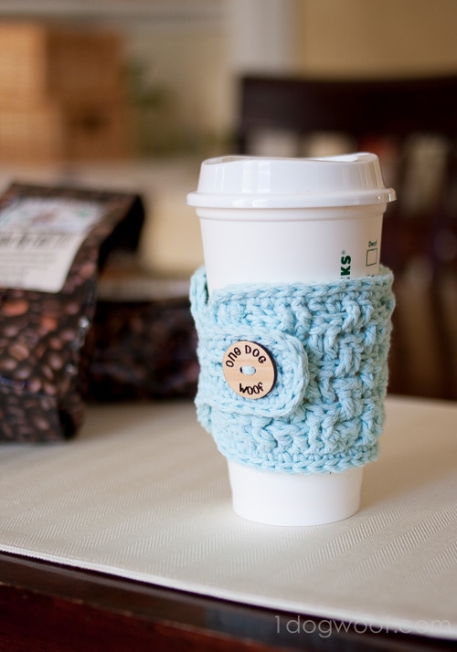 A blue crocheted coffee cozy with a wooden button made for mom from daughter for Christmas.