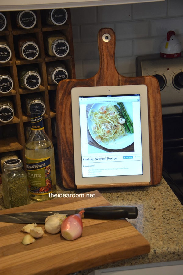 A wooden cutting board that's turned into an iPad holder for cooking recipes in the kitchen.