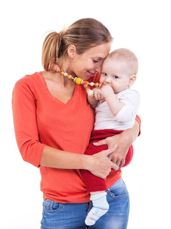 Mom wearing a teething necklace holding a baby who's chewing on it contentedly.